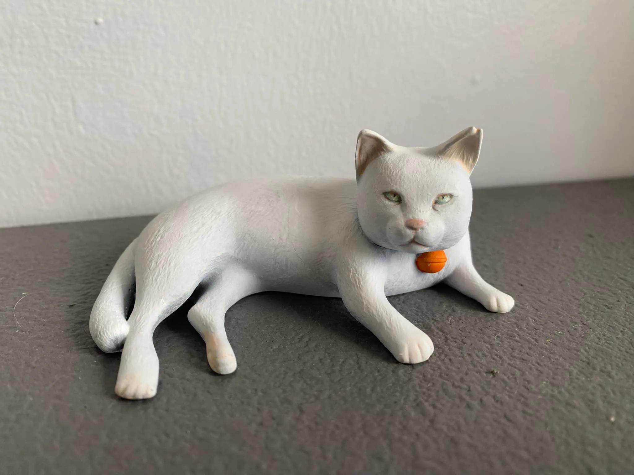 Side view of the white cat sculpture with its red collar