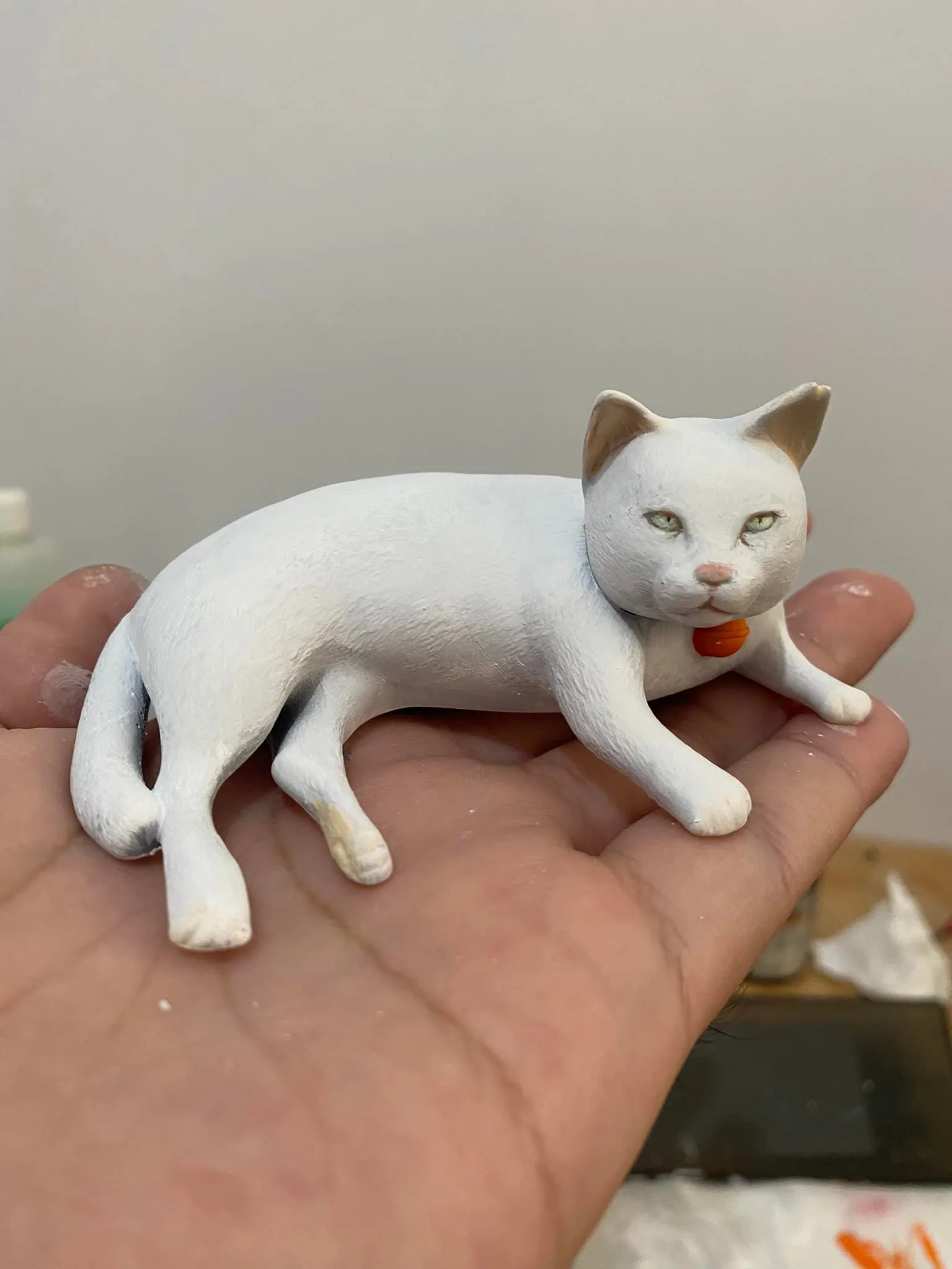 Cat sculpture held in a hand to show its scale